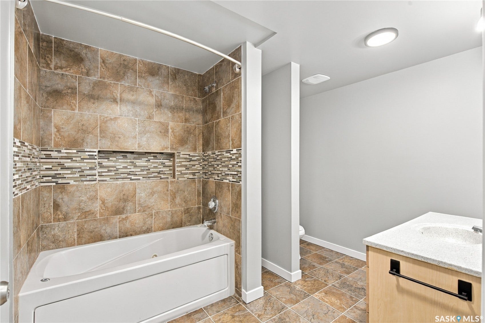 Tiled shower surround with decorative mosaic accent and integrated niche