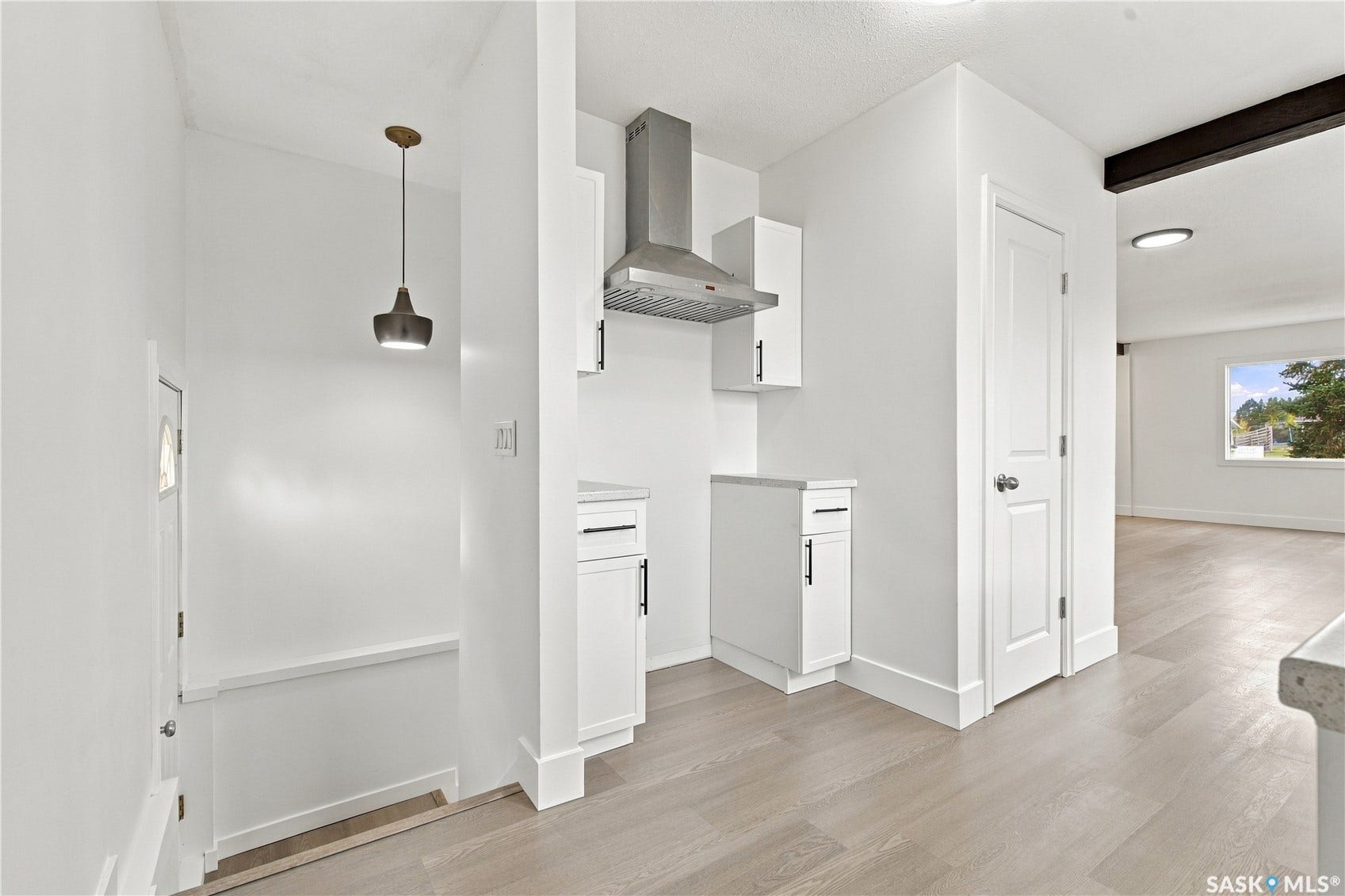 Clean white walls, wood-finish flooring, recessed lighting, and a stainless steel range hood