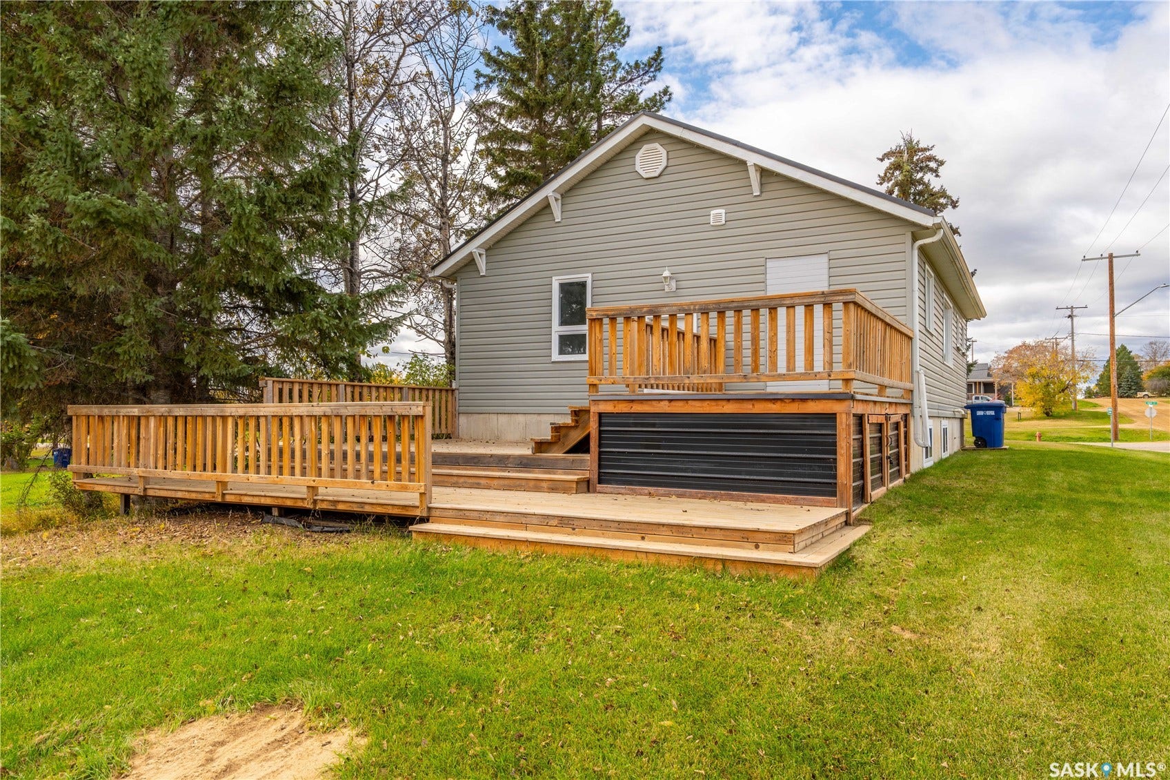 Exterior featuring grey siding, multi-level wood deck, and a green lawn