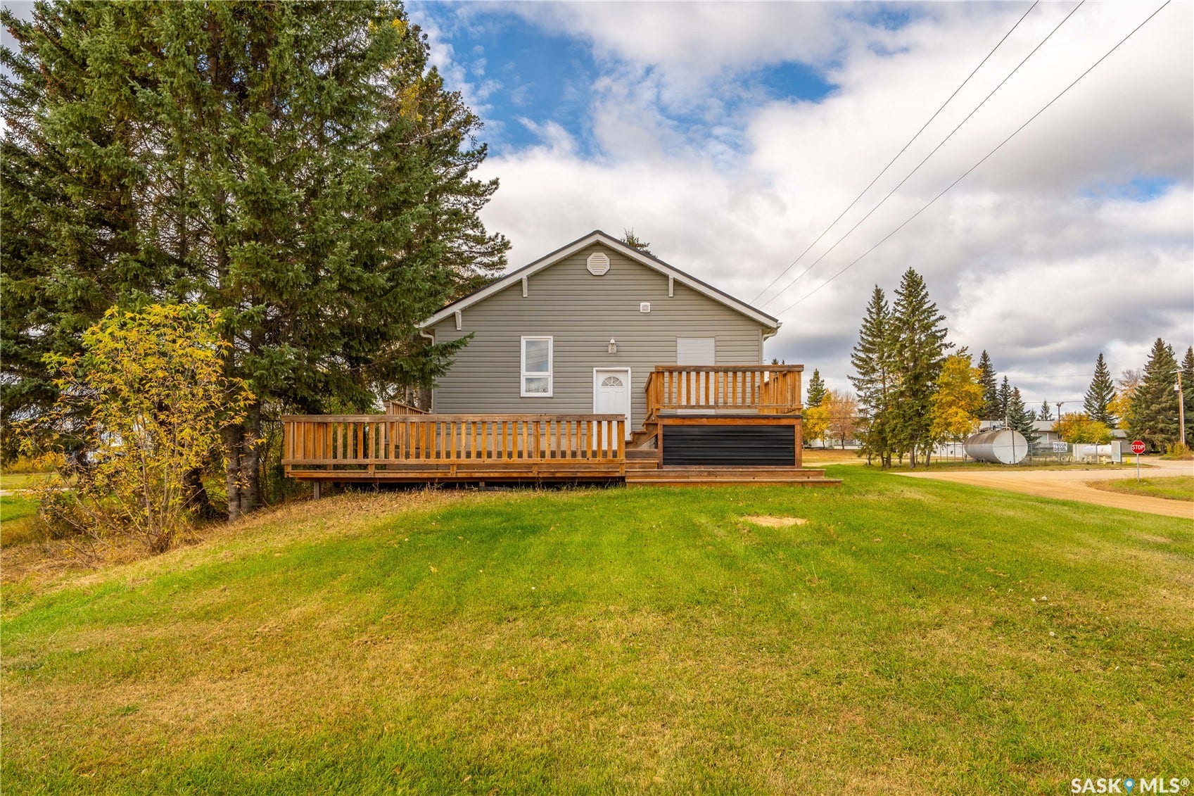 Exterior siding, wood deck, white door, and surrounding mature trees