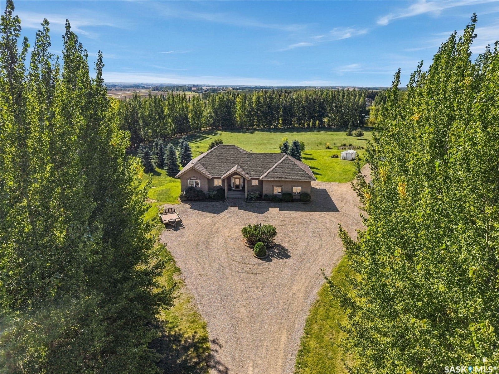Executive style 4 bedroom/ 4 bathroom walk out bungalow with a triple attached garage and an additional shop on just over 5 fully treed and private acres with pavement to the driveway only 10 to 15 minutes from Saskatoon
