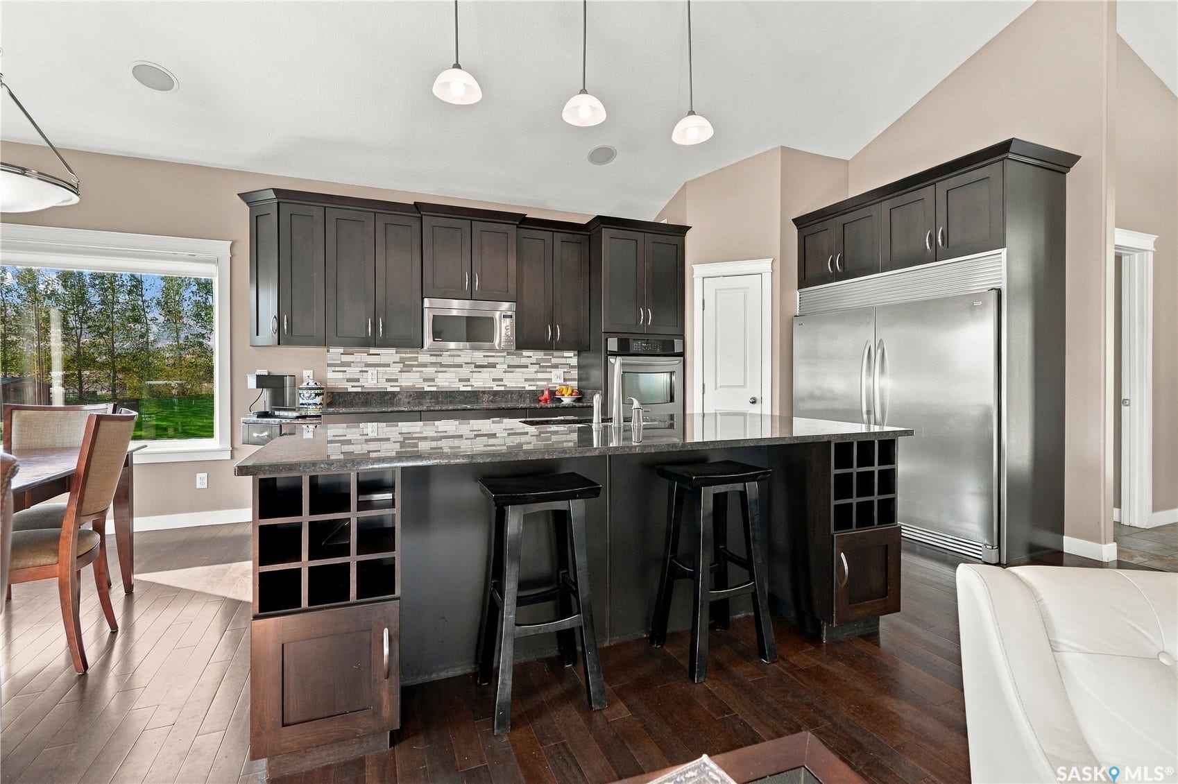 kitchen island features a double sink, wine storage areas, tons of storage and loads of working and eating space on the granite top