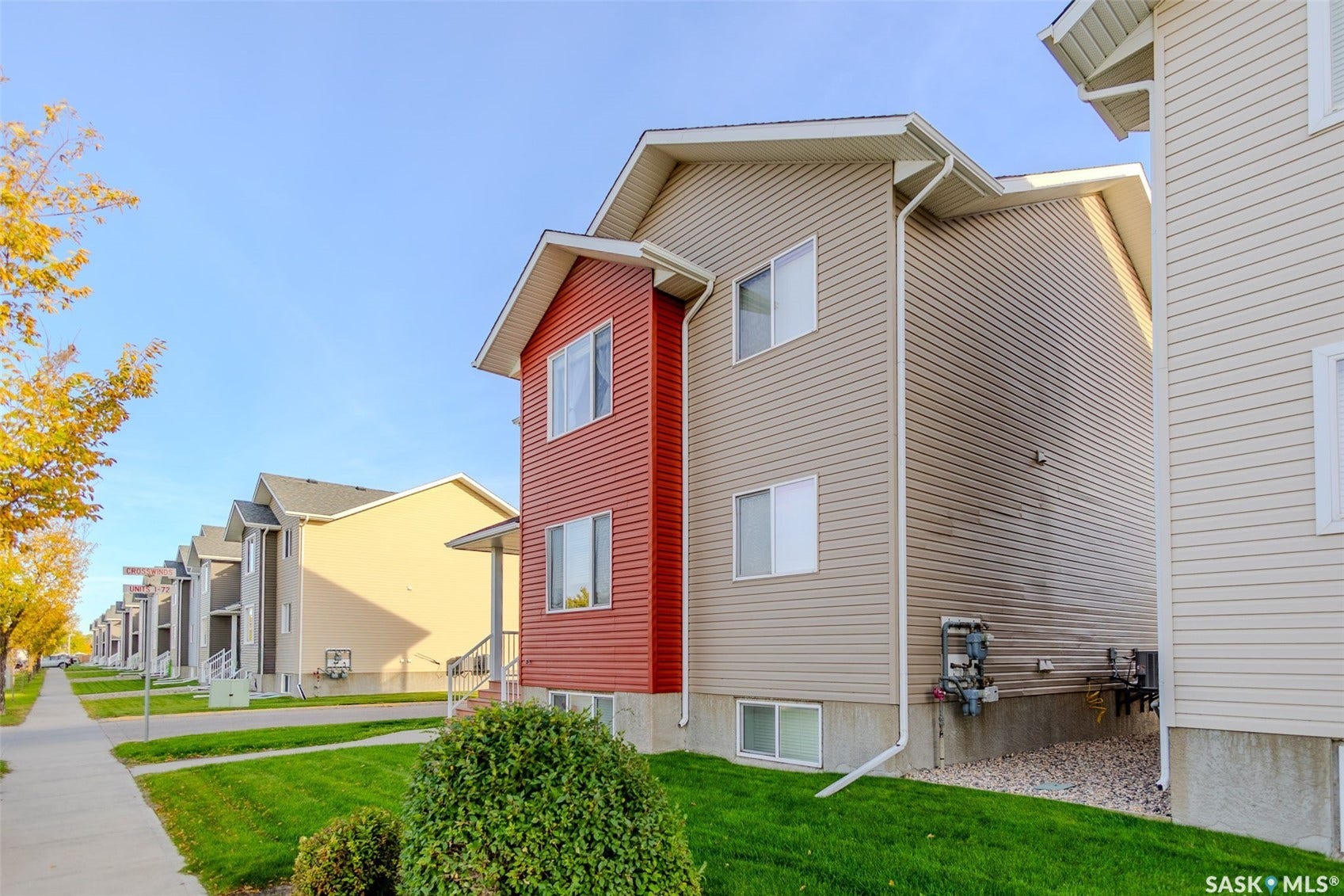 Three-story exterior with red and beige siding, white-framed windows, and a concrete foundation
