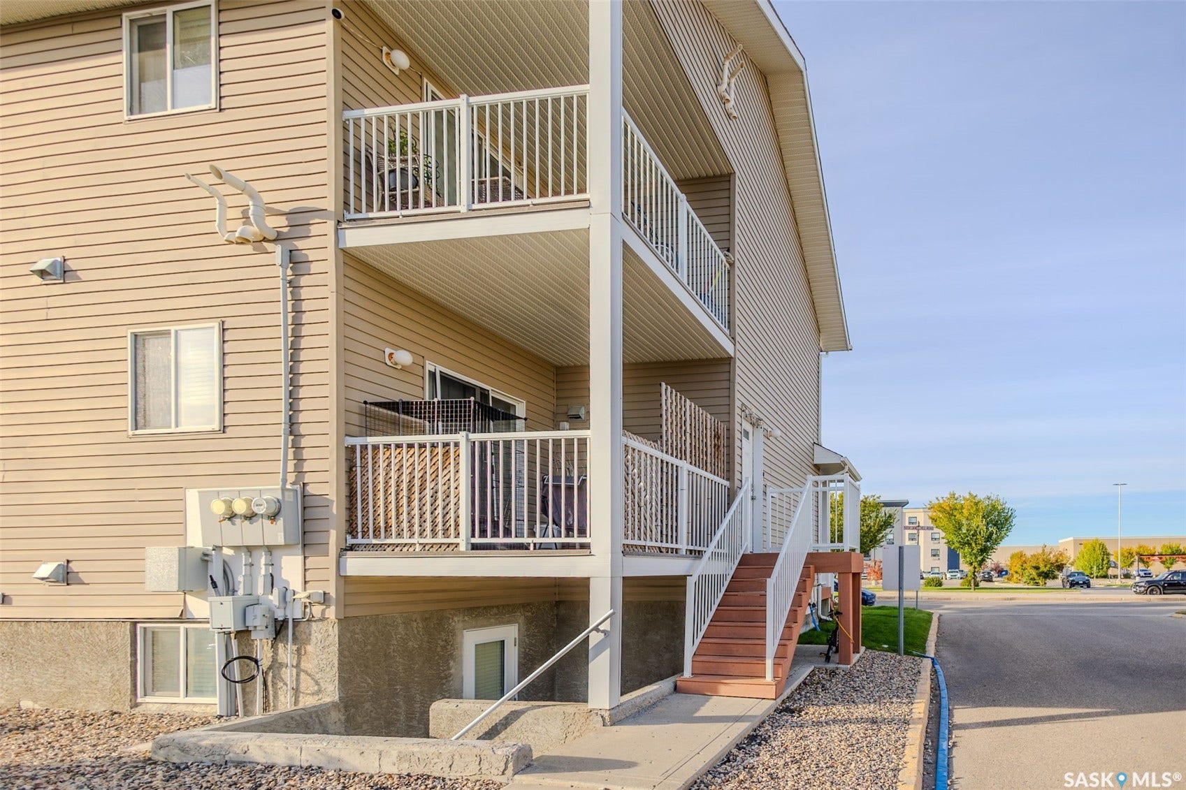 Multi-story building with neutral-toned siding, featuring multiple balconies with white railings