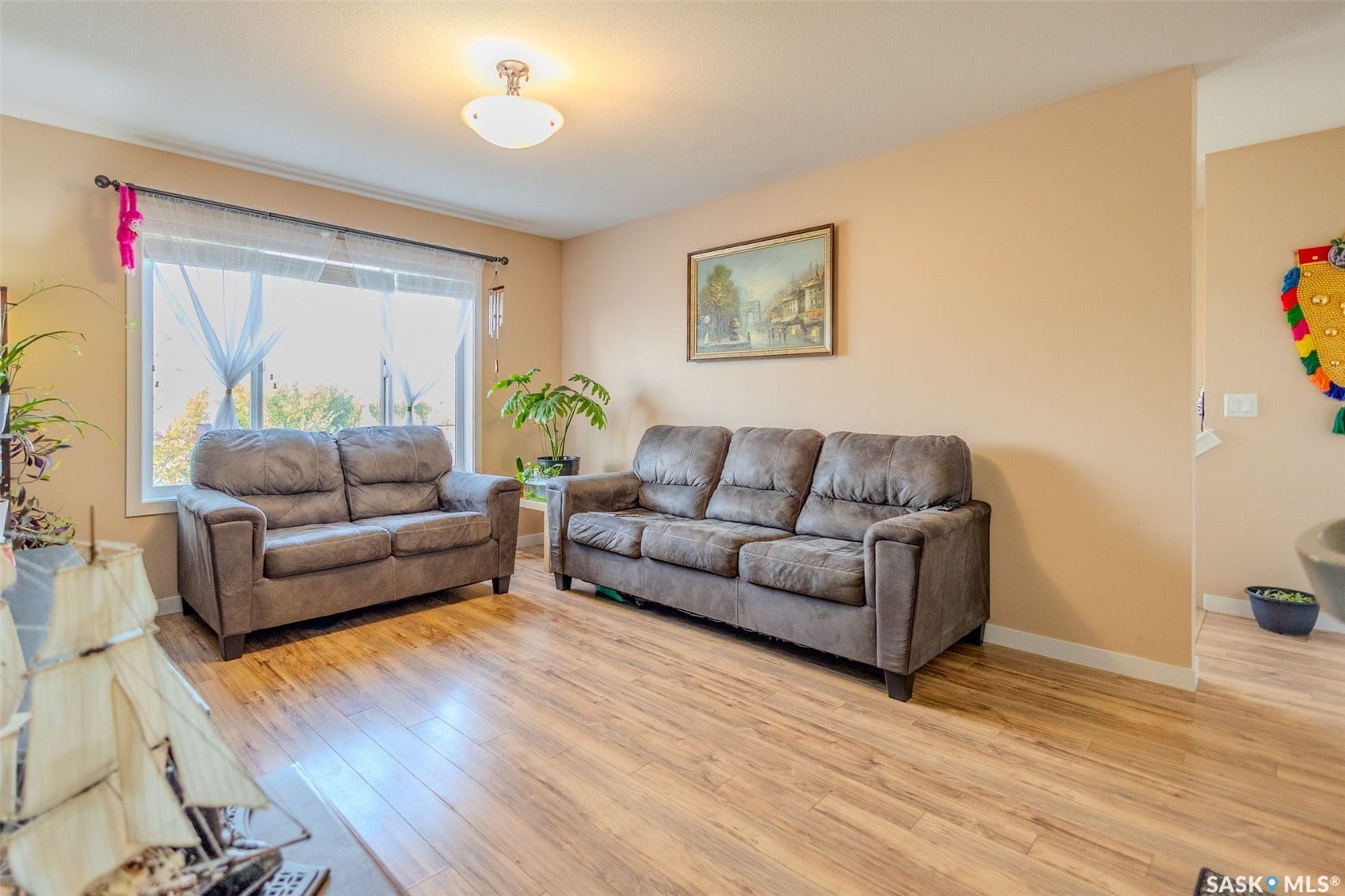 Expansive living area featuring light wood-finish flooring, a large window, and a semi-flush mount ceiling fixture