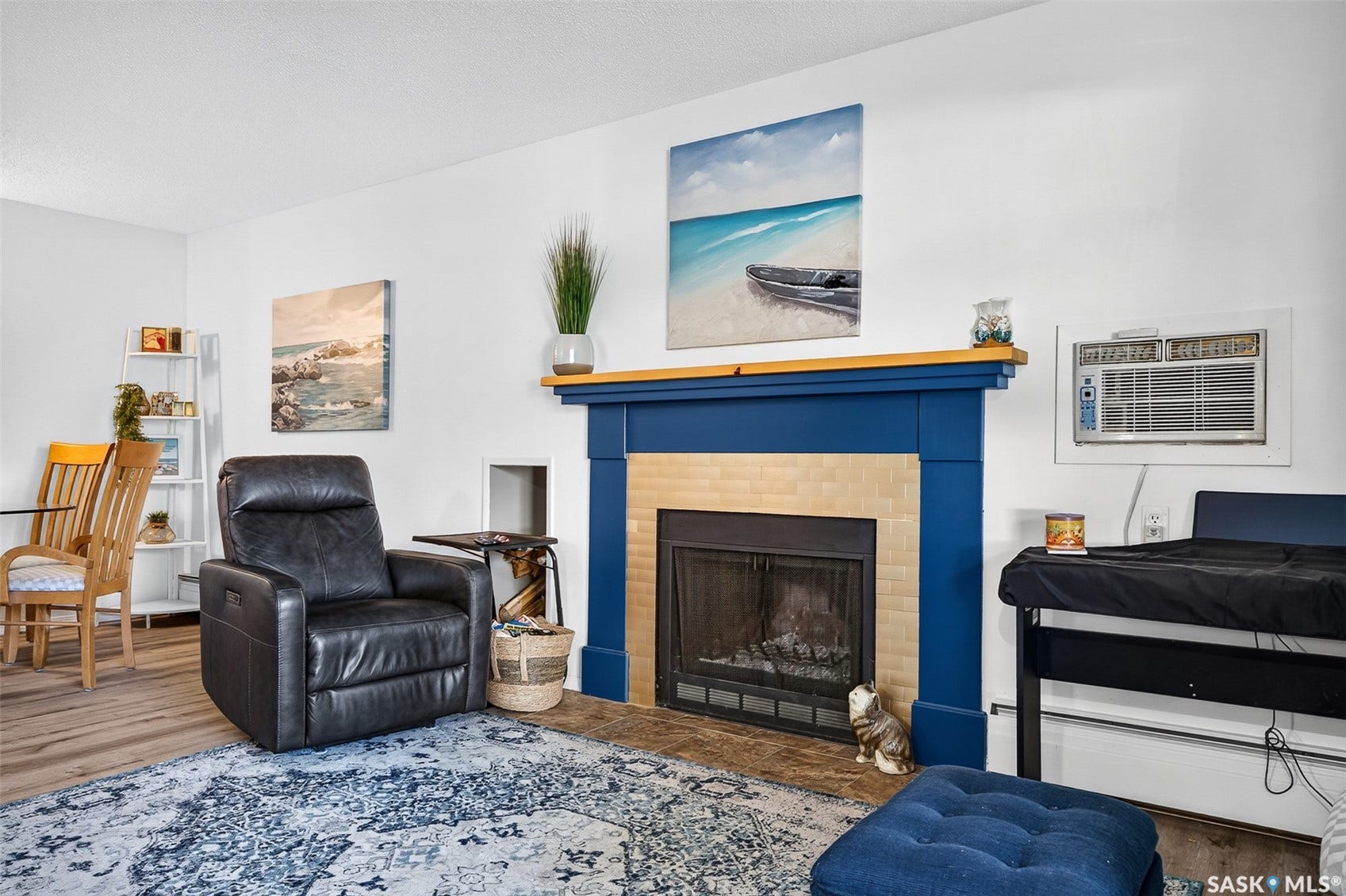 Living area featuring a fireplace with a blue mantel and tan tile surround, wood-finish flooring, and white walls