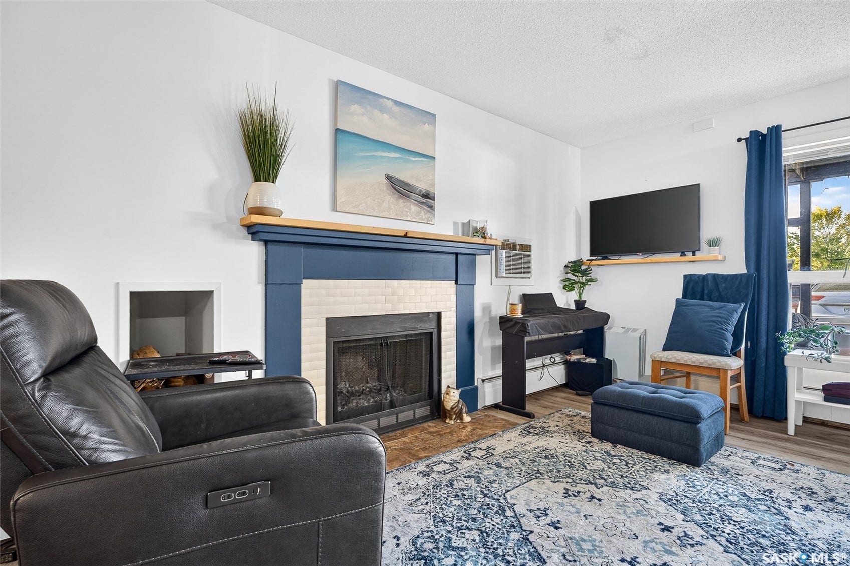 White walls framing a fireplace with a blue mantel and white tile surround, featuring a dark metal firebox