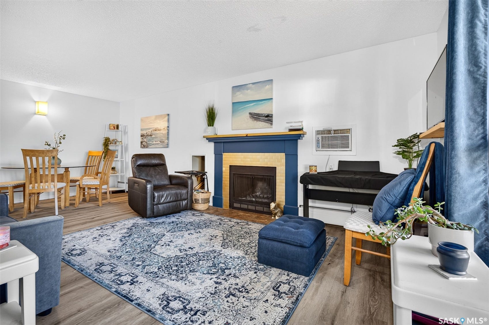 Living area featuring wood-finish flooring, a fireplace with a blue mantel and hearth, and an adjacent dining space with a glass-top table
