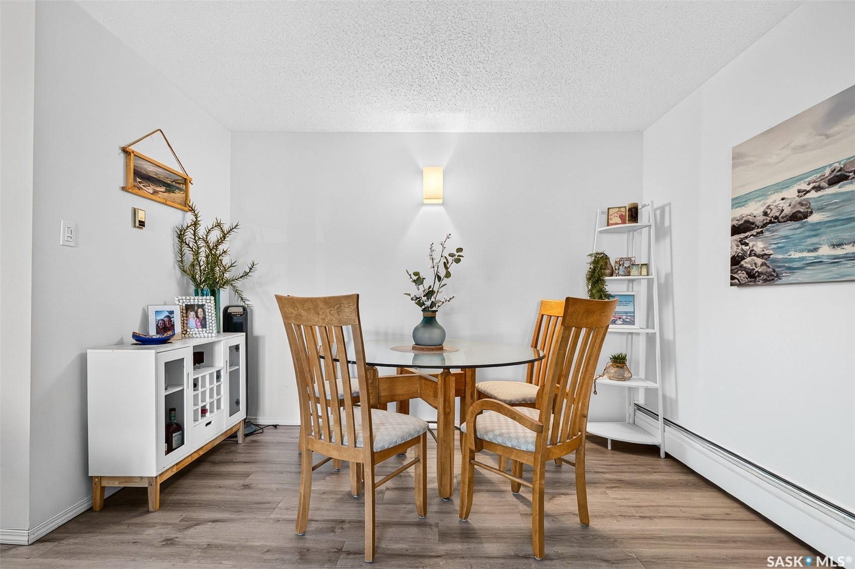 Wood-finish flooring, white walls, built-in baseboard heating, and a wall-mounted sconce