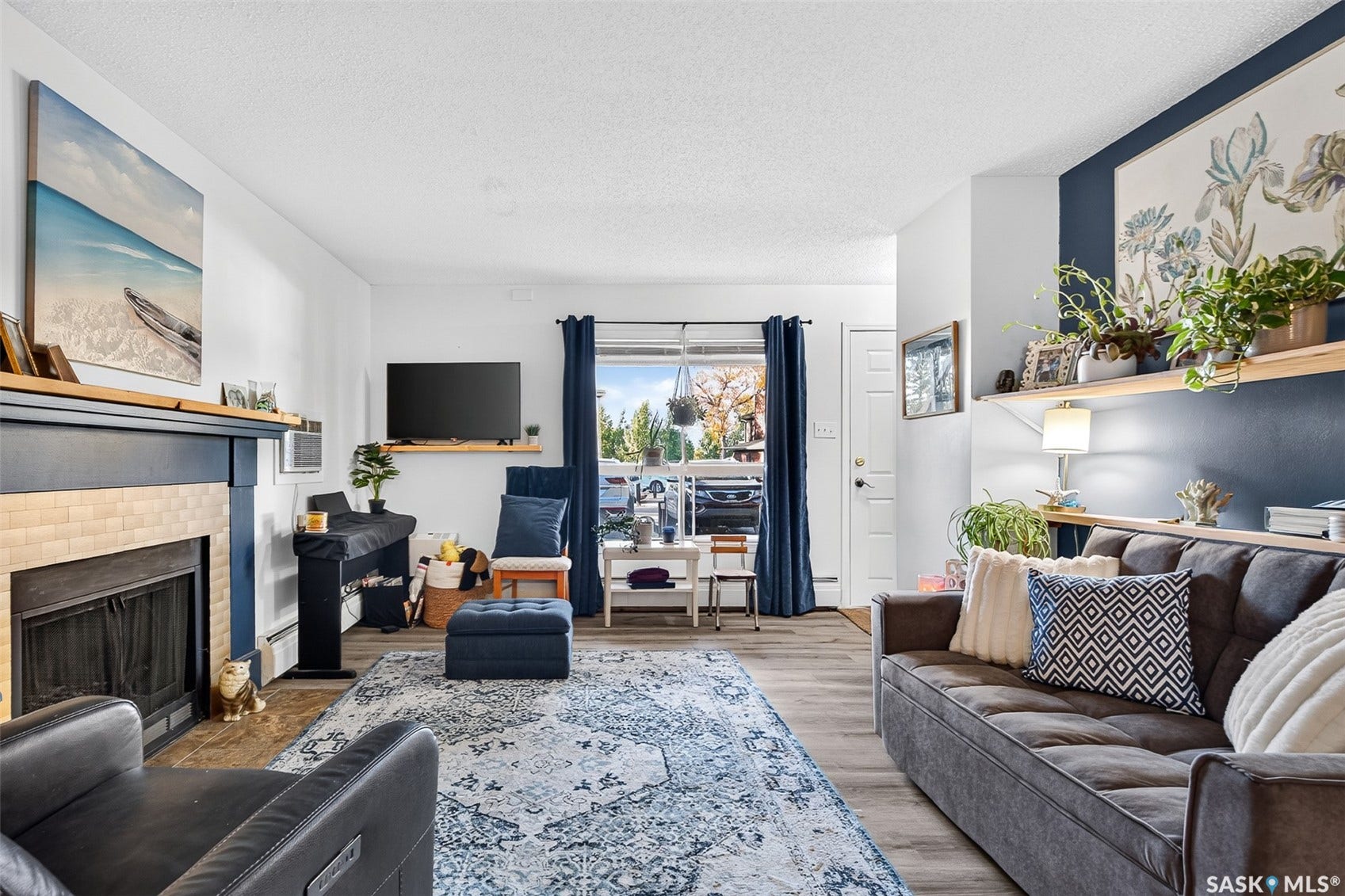 Living area featuring a fireplace with a tiled surround, wood-finish flooring, and a window with exterior visibility