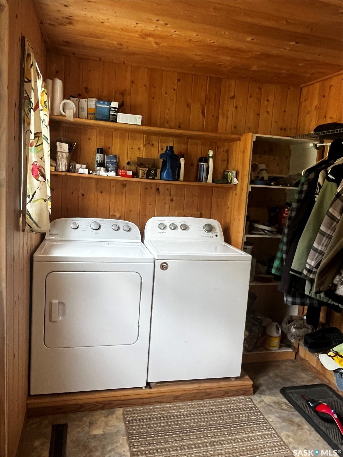 Laundry area featuring paneled walls, two wall-mounted shelves, and a built-in shelving unit