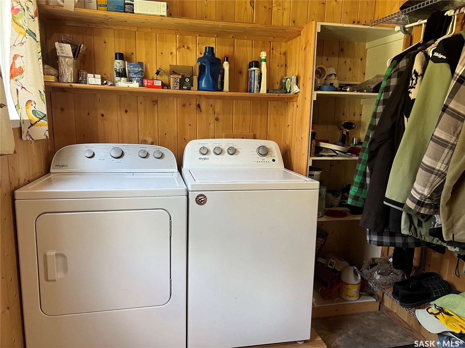 Laundry area featuring wood-paneled walls, built-in shelving, and a washer and dryer unit
