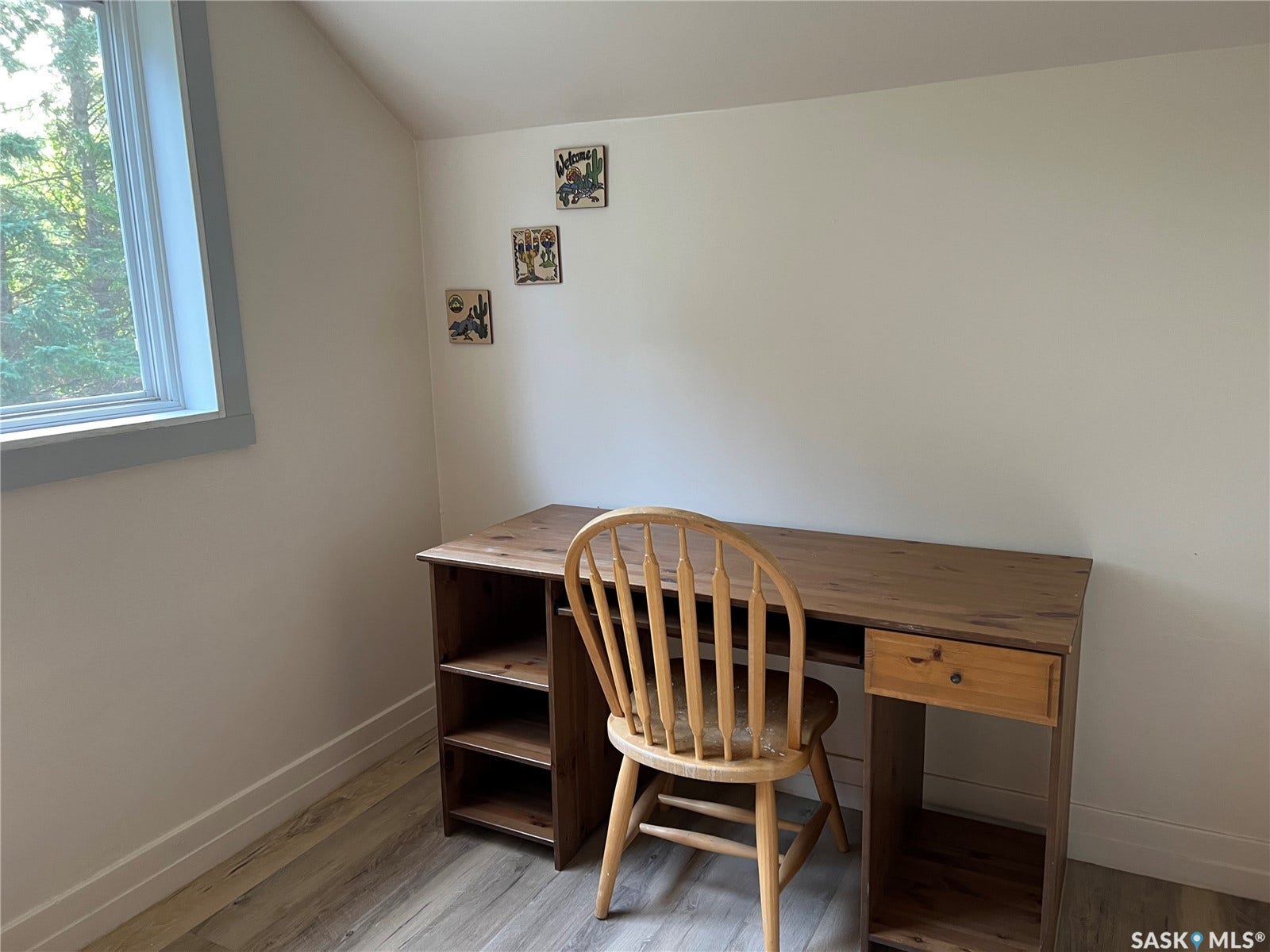 Light-toned walls, wood-finish flooring, and a single window with painted trim