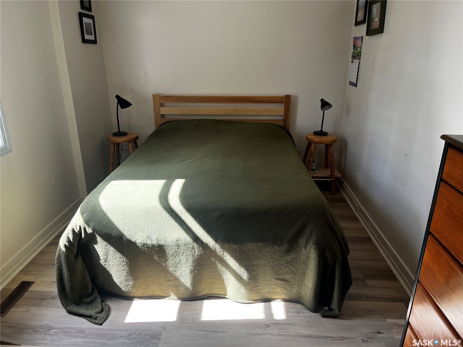 Wood-finish flooring with white baseboards, a light-colored wall finish, and a window with white trim