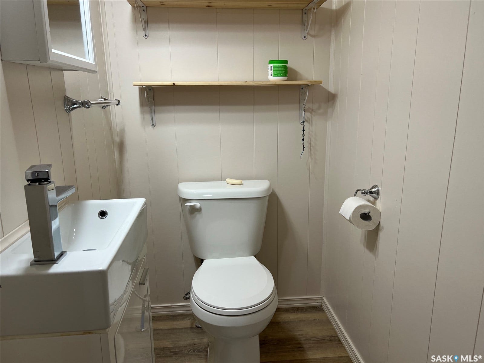 Modern square vessel sink with a contemporary chrome faucet, wall-mounted wood shelves, wood-finish flooring, and vertical paneling