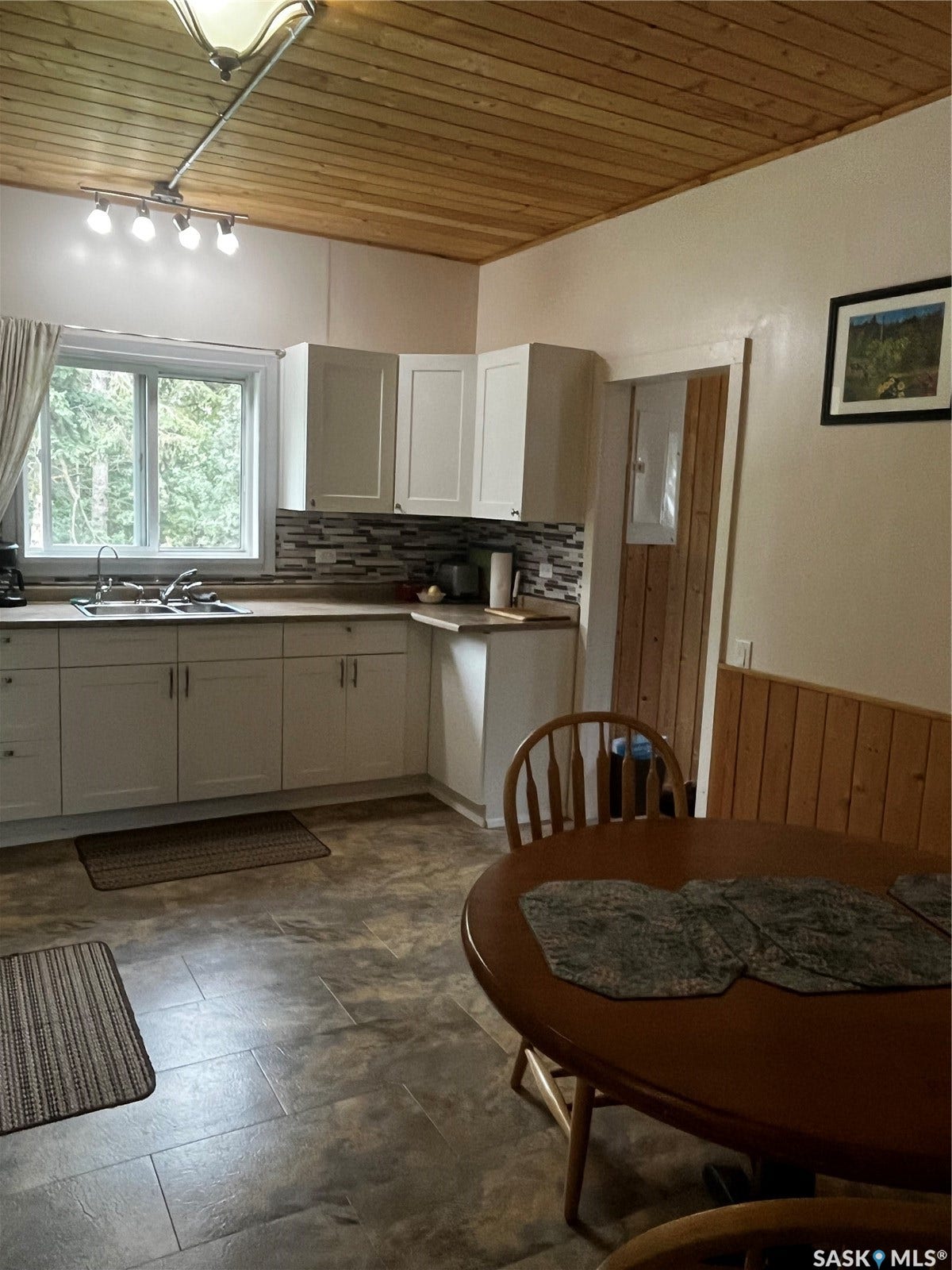Kitchen featuring a wood-panel ceiling, white cabinetry, a tile backsplash, and a window above the sink