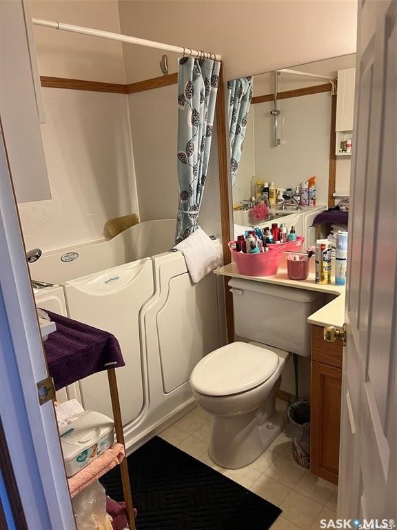 Bathroom featuring a walk-in bathtub, a toilet, a vanity with a white countertop, and a wall mirror