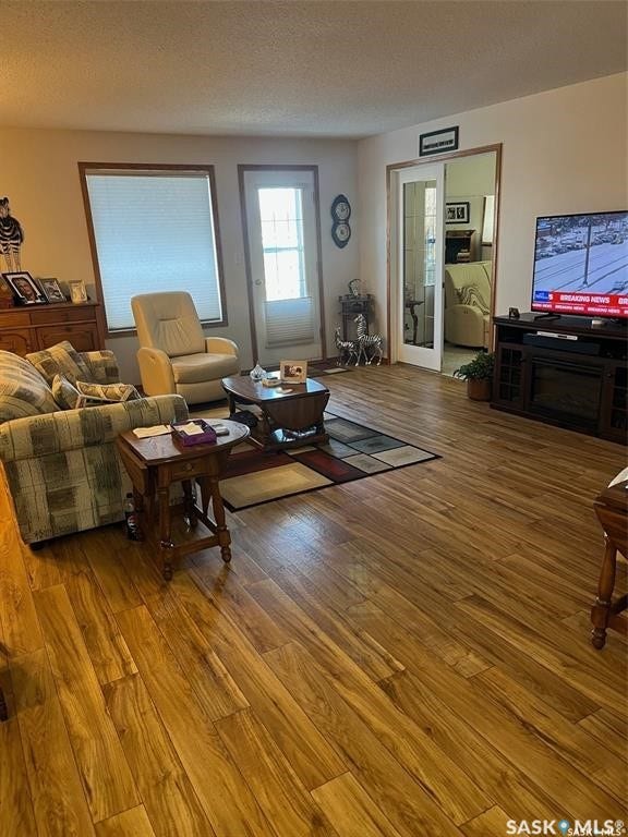 Wood-finish flooring throughout, multiple windows with blinds, and a glass-paneled entry door