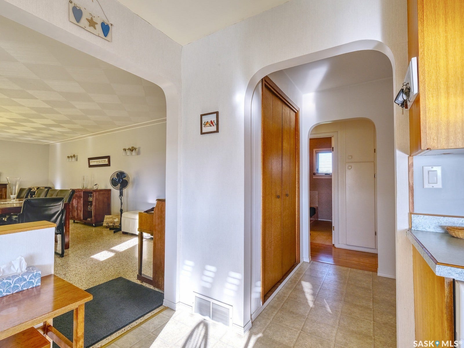 Arched doorways, tiled flooring, wood-finish closet doors, and wood-finish cabinetry