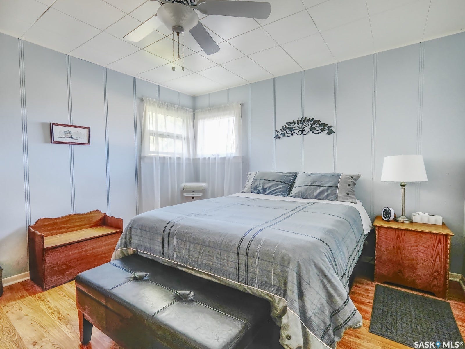 Wood-finish flooring, paneled walls, and a ceiling fan with integrated lighting