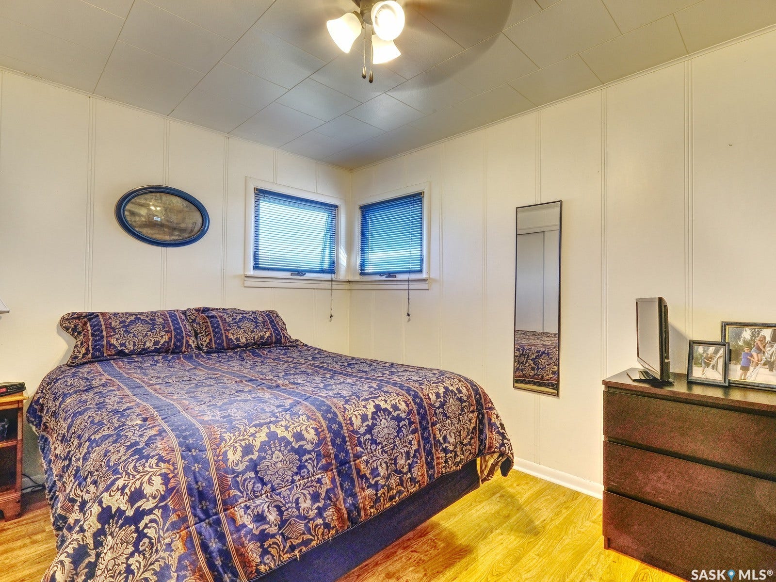 Wood-finish flooring with white paneled walls and a ceiling fan
