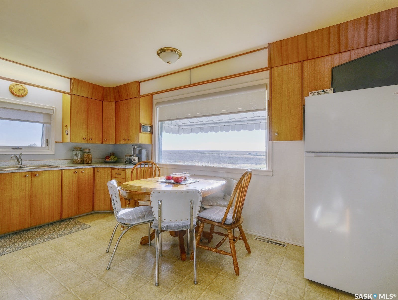 Wood-finish cabinetry with coordinating paneling, light-toned tiled flooring, and a built-in kitchen sink with a light-colored countertop