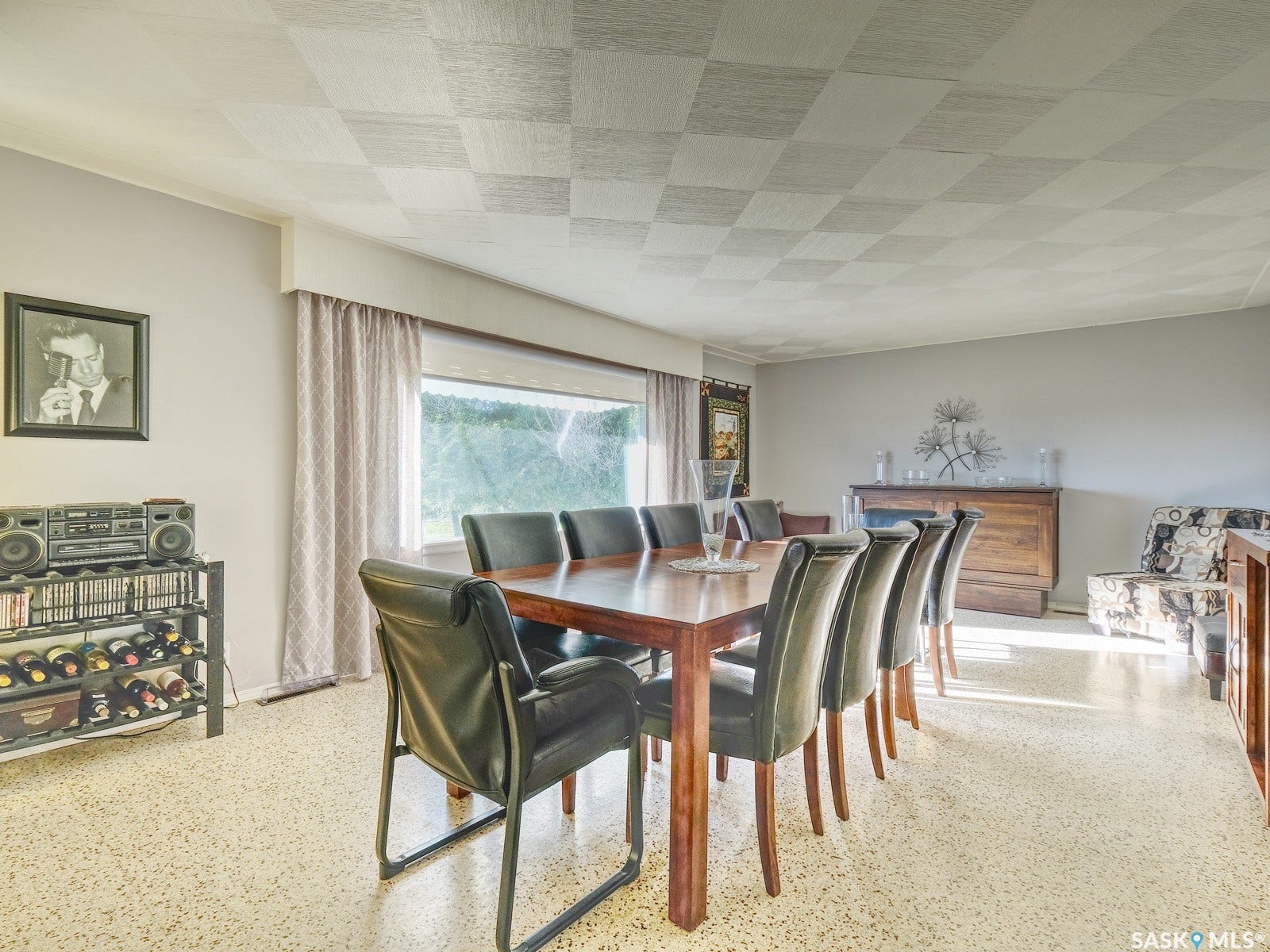 Expansive room with checkerboard ceiling design, large picture window, and light-toned terrazzo-style flooring