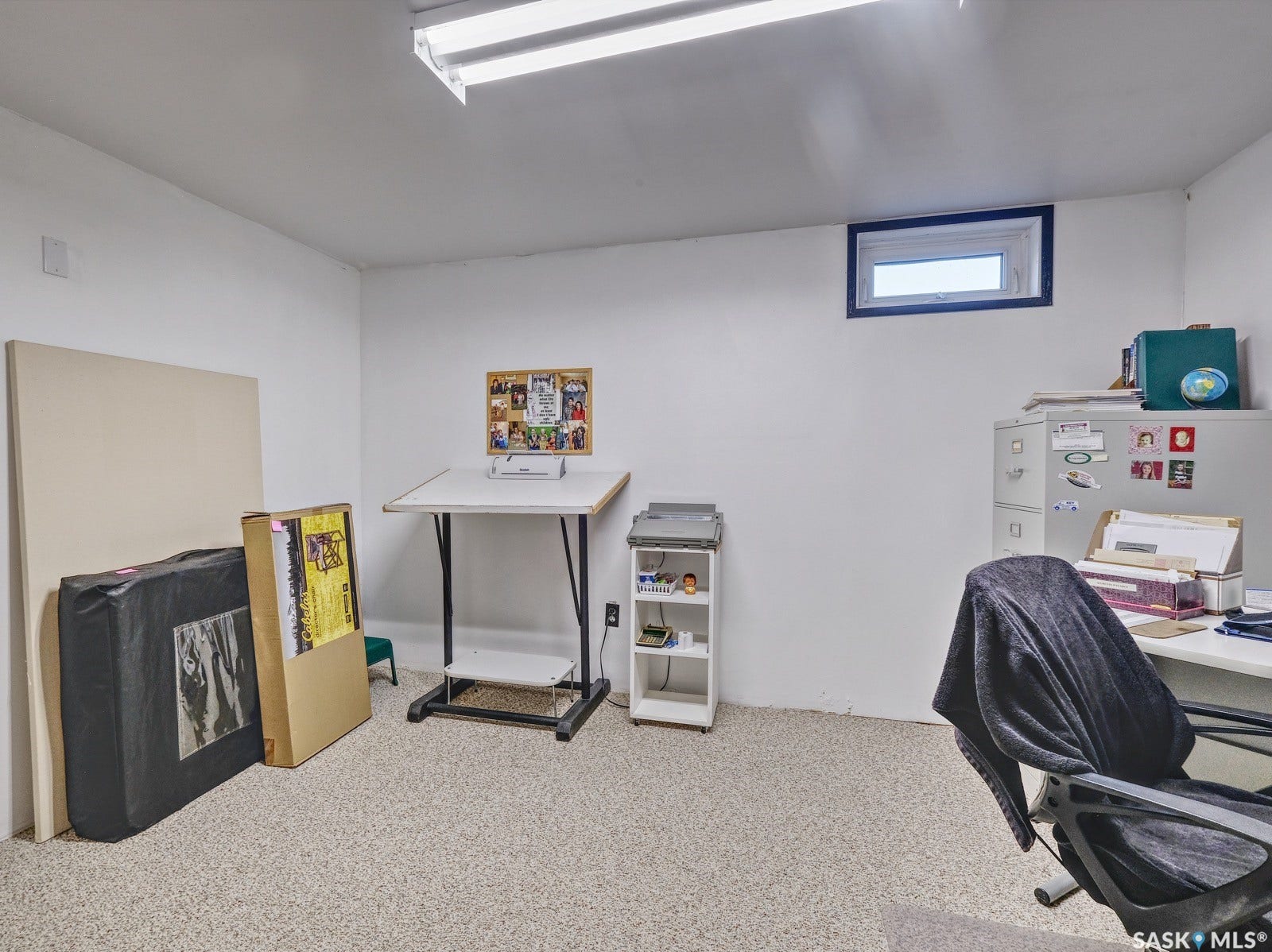 Recessed window with dark trim, overhead fluorescent lighting, and light-colored textured flooring