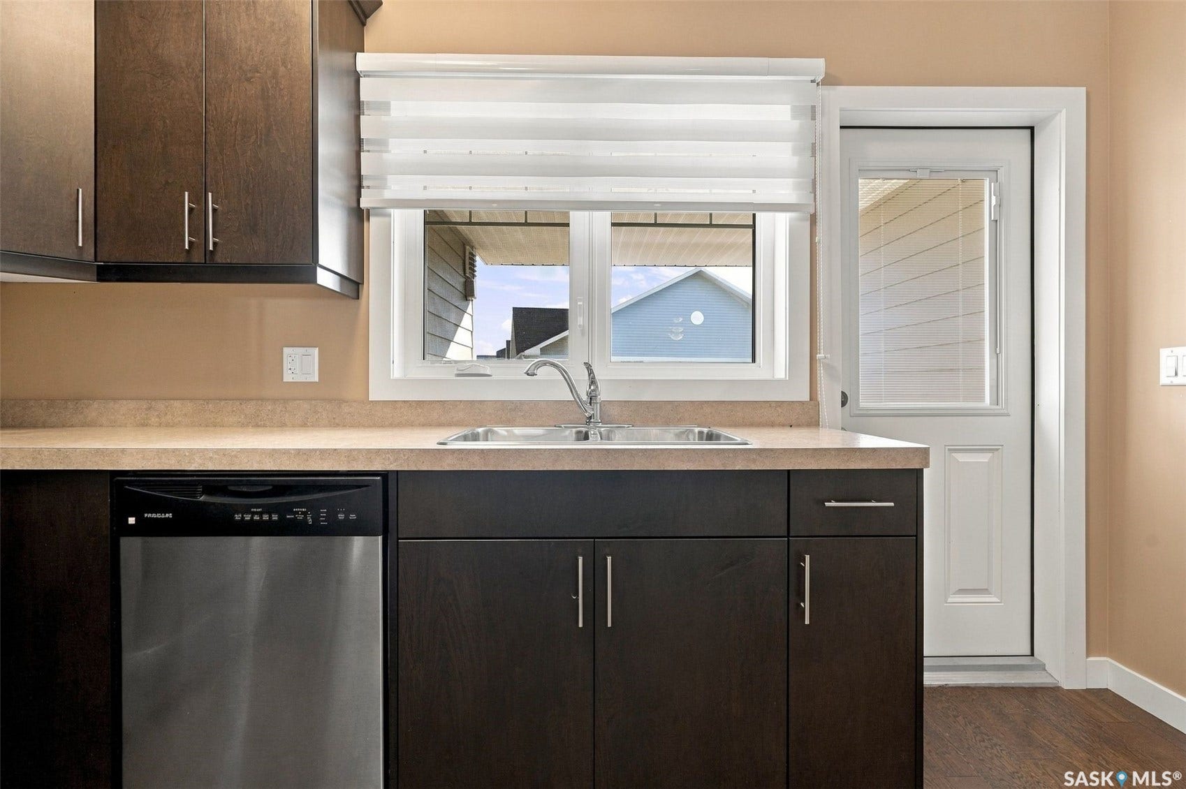 Stainless steel dishwasher, single basin sink, dark wood-finish cabinetry, light-toned countertop
