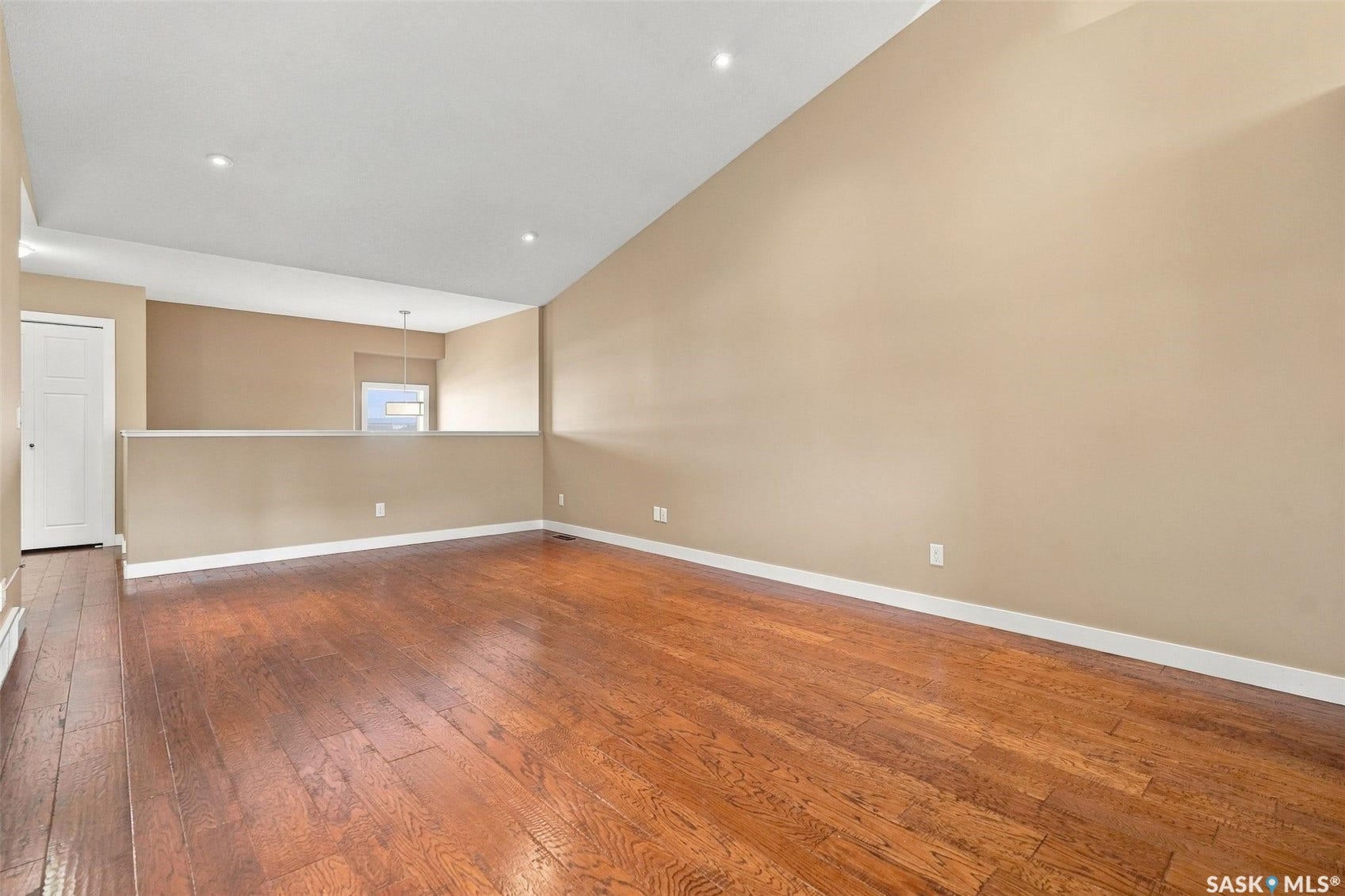 Spacious room featuring rich wood-finish flooring, recessed lighting, and a neutral color palette