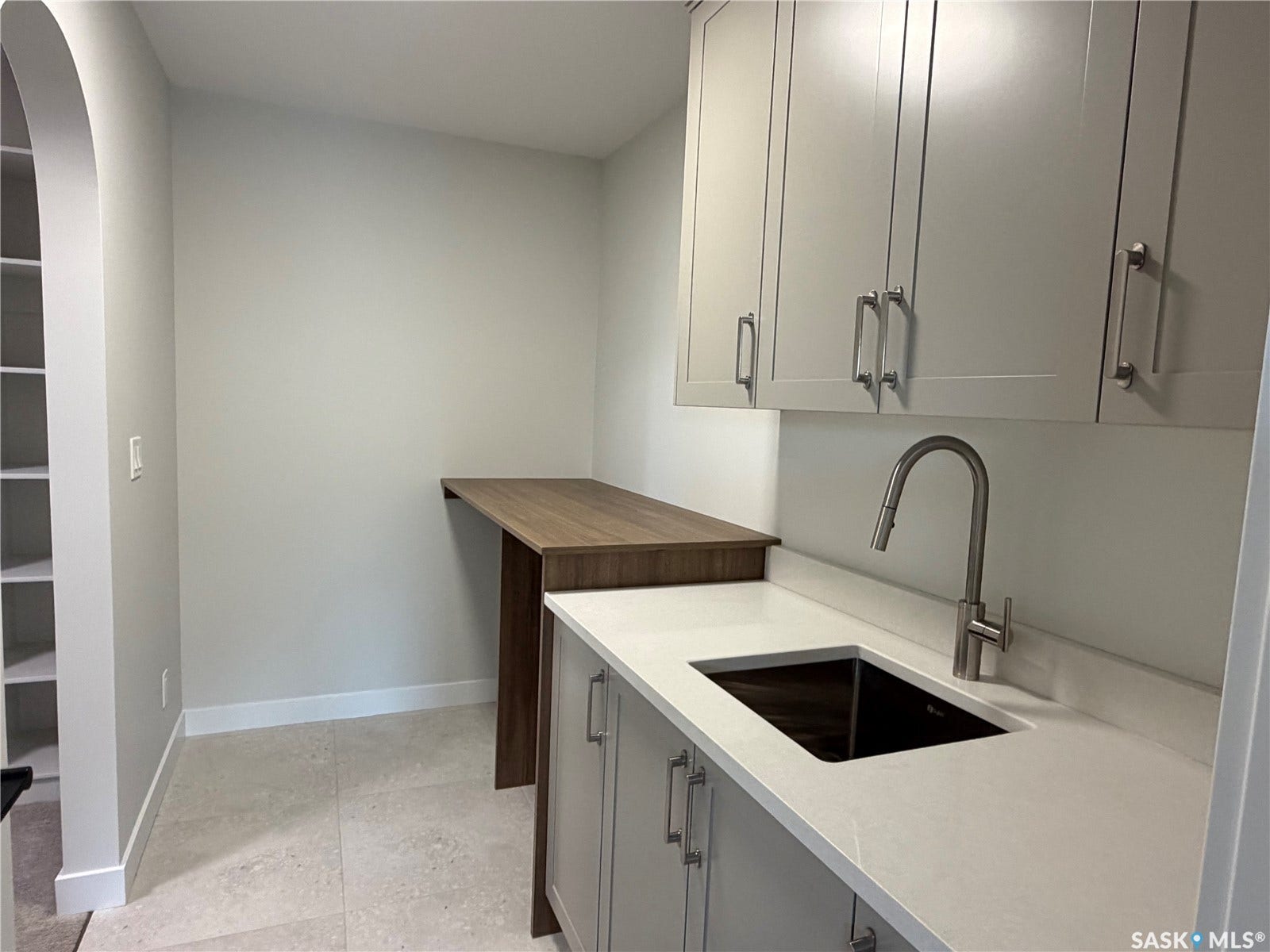 310 Traeger Manor, Saskatoon SK S7V 1Z4 Built-in cabinetry with brushed nickel hardware, white stone-finish countertop, undermount sink with a pull-down faucet, and wood-finish accent counter