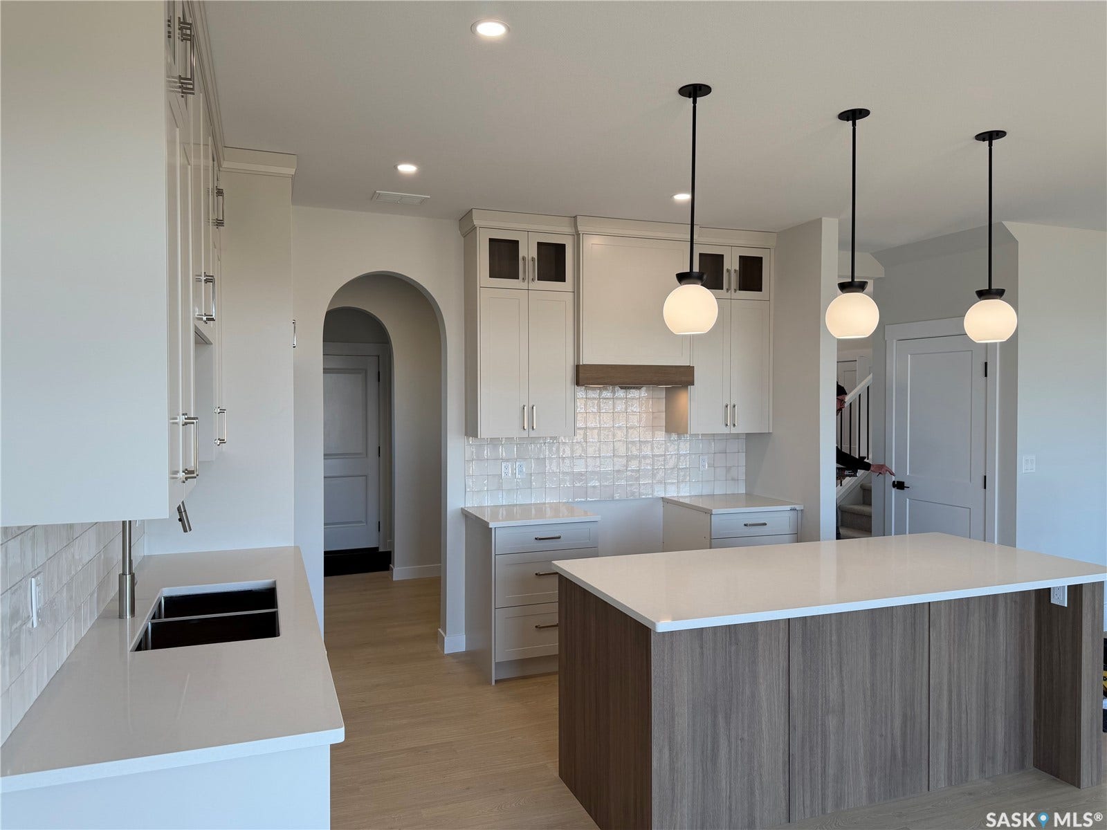 310 Traeger Manor, Saskatoon SK S7V 1Z4 Modern kitchen featuring an expansive island with a light wood-finish base, three pendant light fixtures, and recessed ceiling lighting
