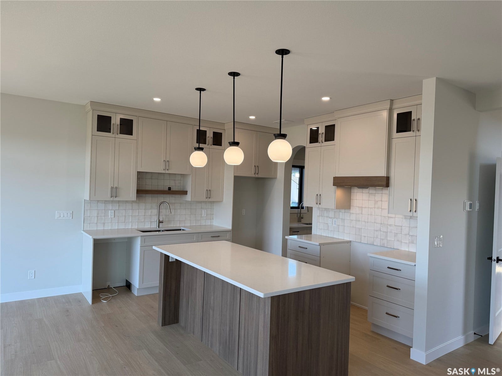 310 Traeger Manor, Saskatoon SK S7V 1Z4 Kitchen featuring a large island with a light-colored countertop, light-toned cabinetry, and a white tile backsplash