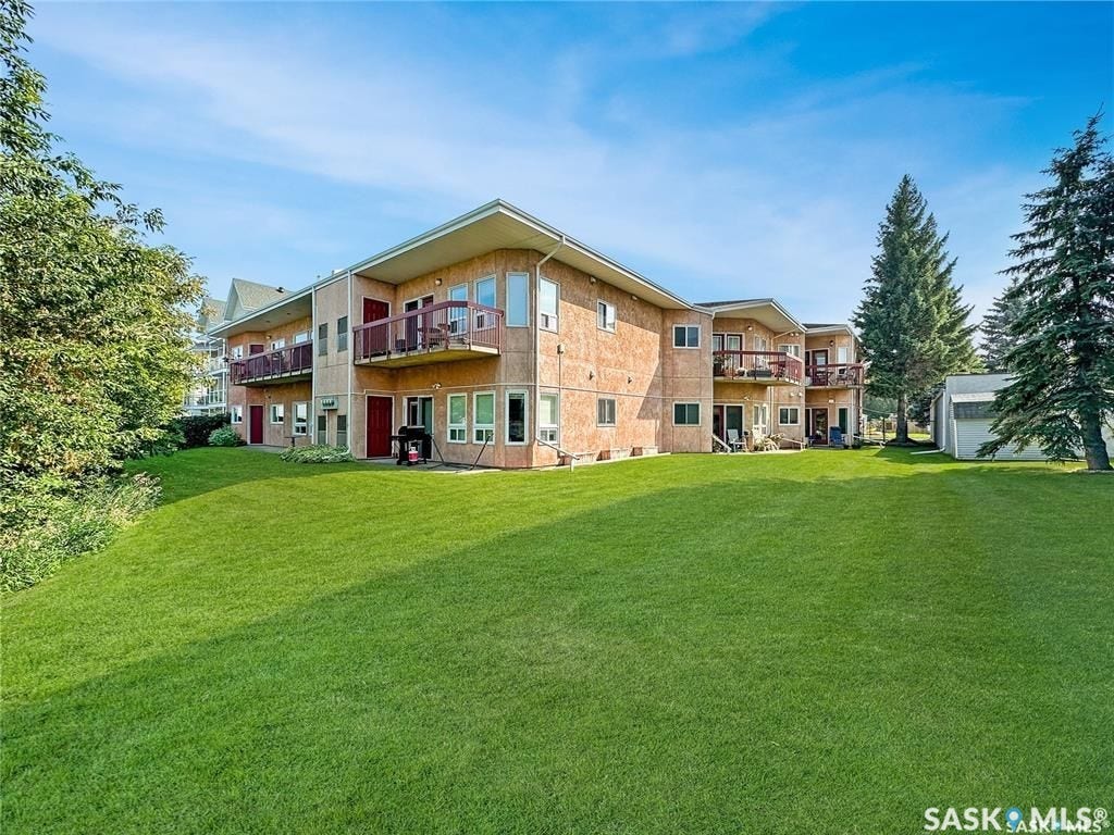 Expansive green space featuring a multi-unit building with exterior balconies and multiple entry points