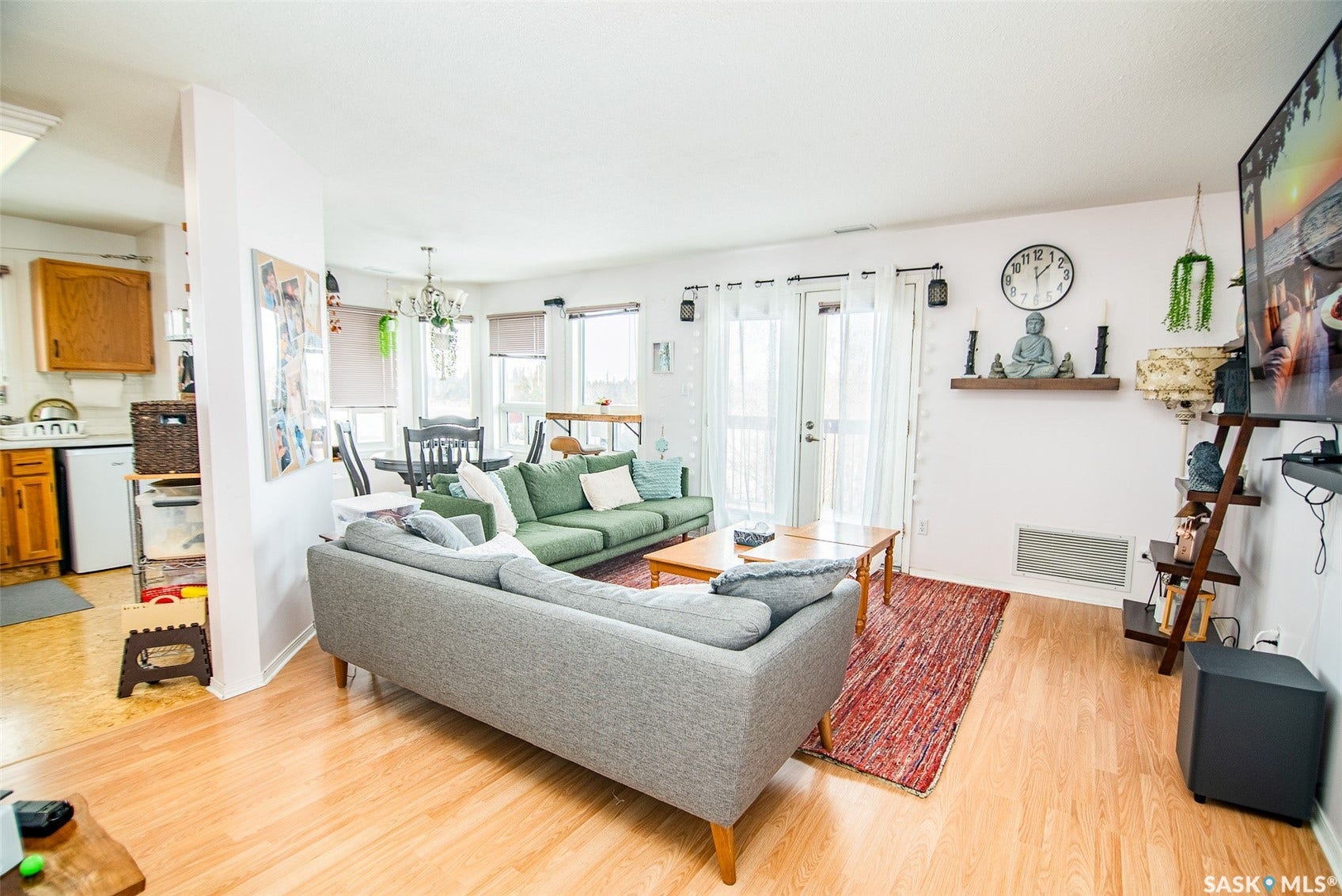 Open-concept living space featuring wood-finish flooring, a dining area with a chandelier, and a kitchen with wood cabinetry