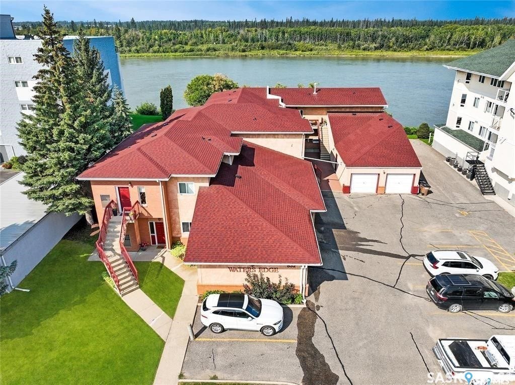 Building exterior with red asphalt shingle roof, direct water frontage, attached garage, and exterior staircase