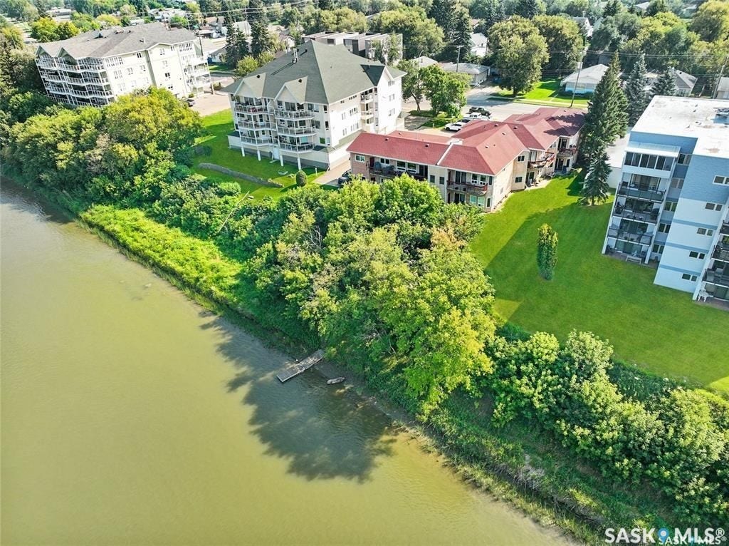 Riverfront property featuring a private dock, lush green spaces, and mature trees