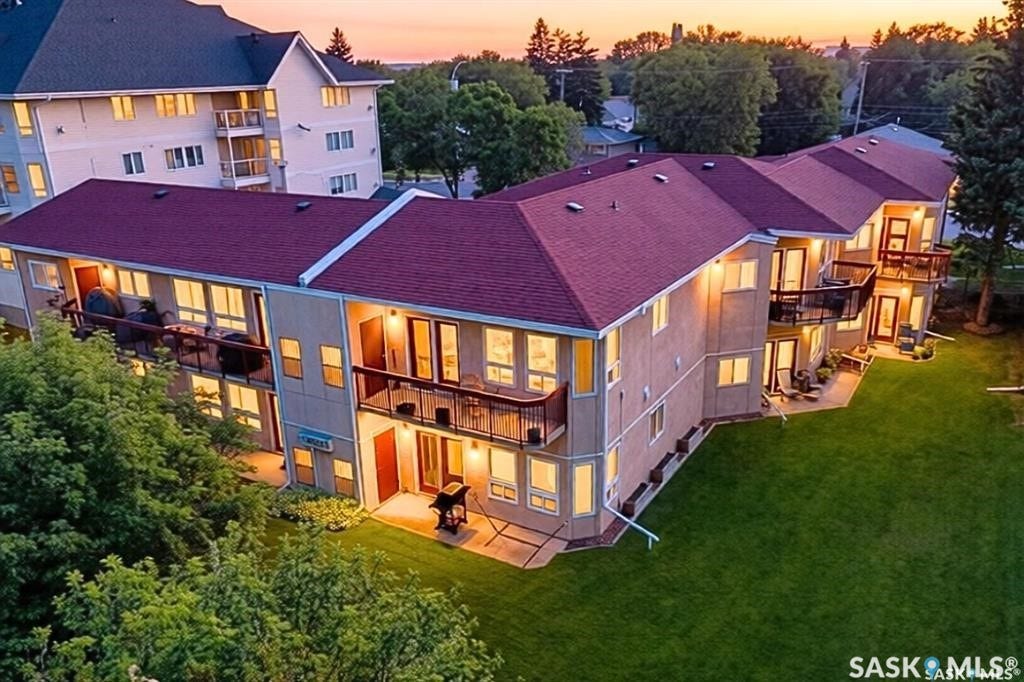 Multi-level residential building featuring private balconies, individual patios, and a manicured lawn area