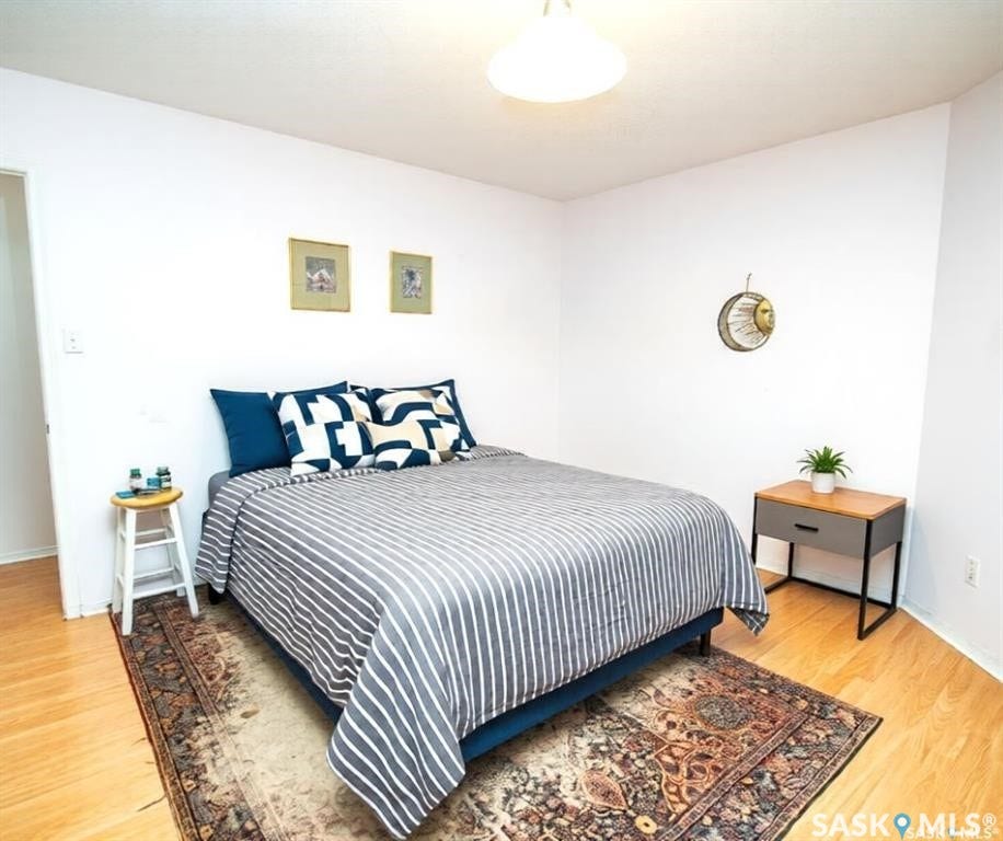 Hardwood-finish flooring, white painted walls, and a ceiling-mounted light fixture