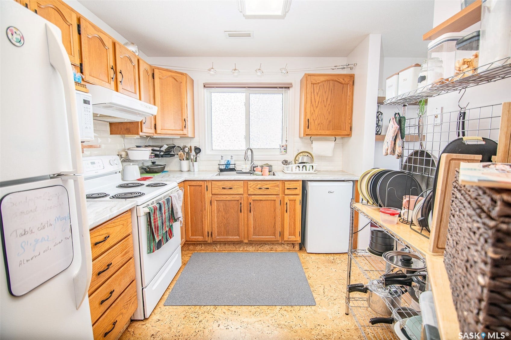 Kitchen featuring wood-finish cabinetry, white appliances, solid surface countertops, and a stainless steel sink
