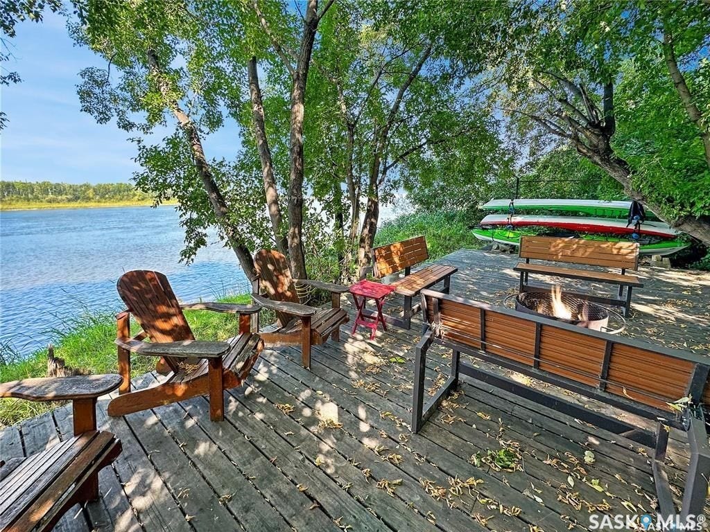 Riverfront property featuring a wood deck, Adirondack chairs, and a fire pit