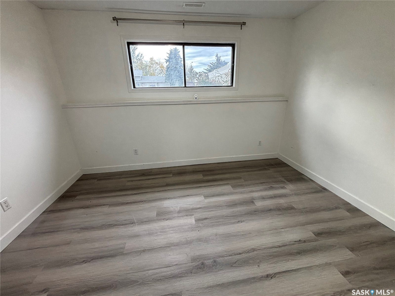Light-toned wood-finish flooring with white baseboards and painted walls