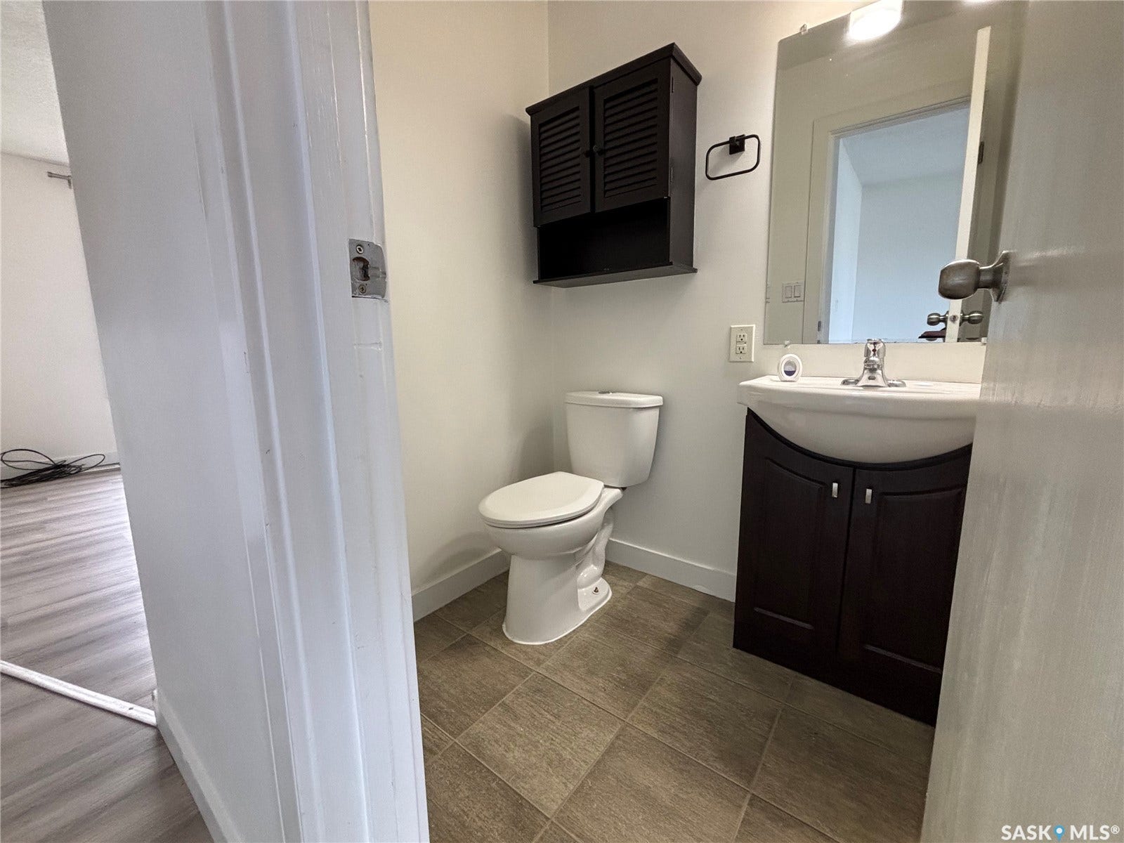 Recessed lighting, wood-finish flooring, dark wood-finish vanity, wall-mounted mirror, and dark wood-finish storage cabinet