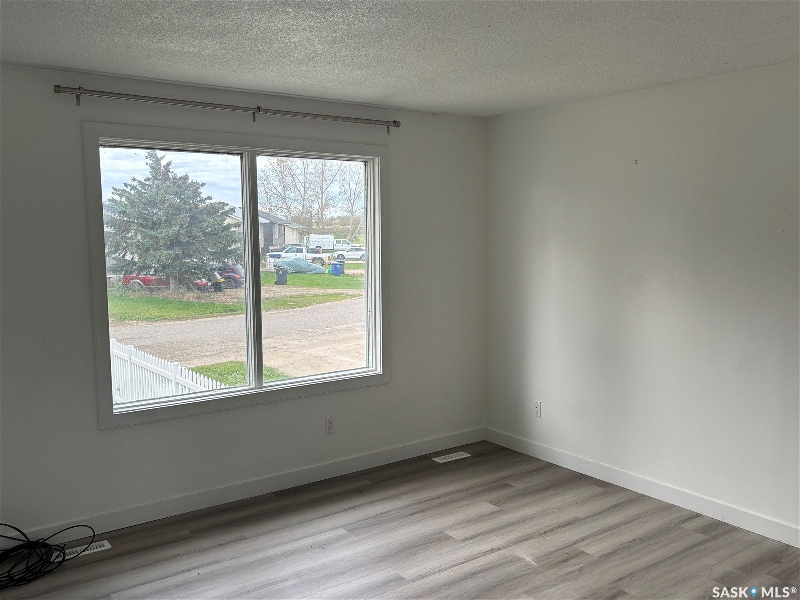 Bright interior space featuring a large window, neutral wall finishes, and wood-finish flooring