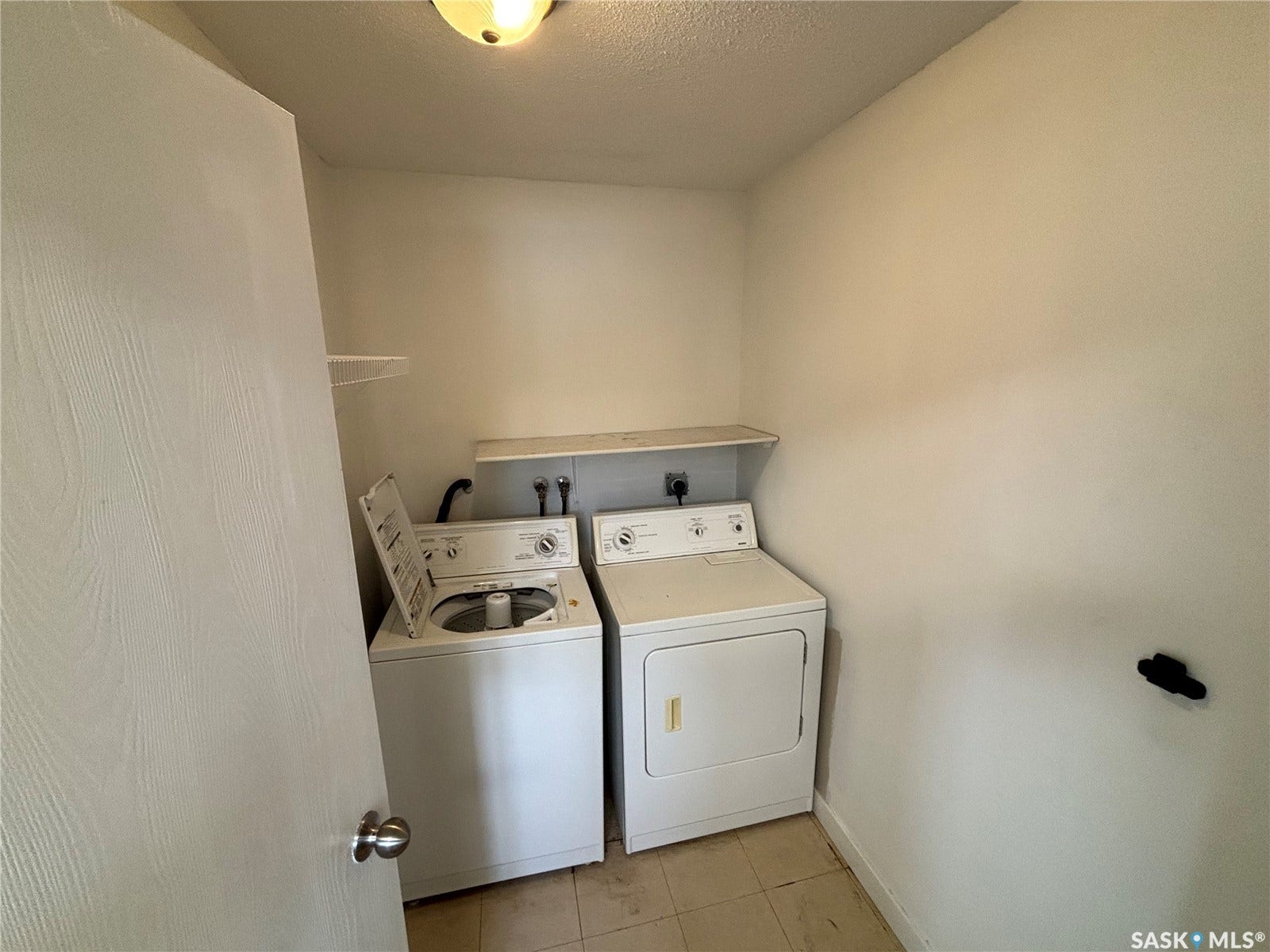 Dedicated laundry area with tile flooring and a built-in shelf