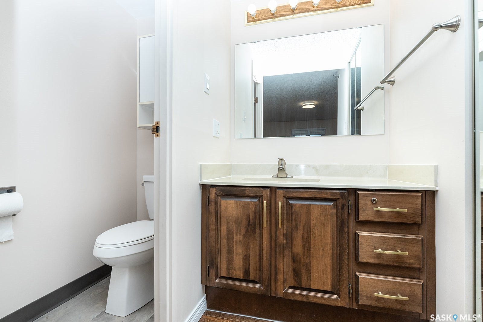 2-piece ensuite bathroom featuring a wood-finish vanity with a light-toned countertop and integrated sink