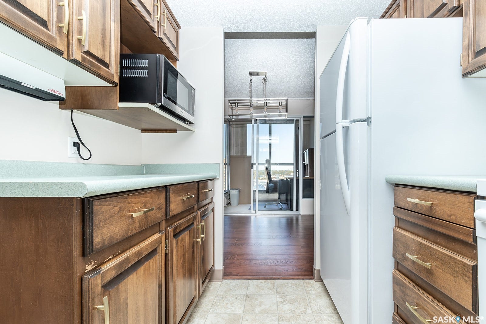 Kitchen featuring wood cabinetry, light-toned countertops, a double basin sink, white appliances and linoleum flooring