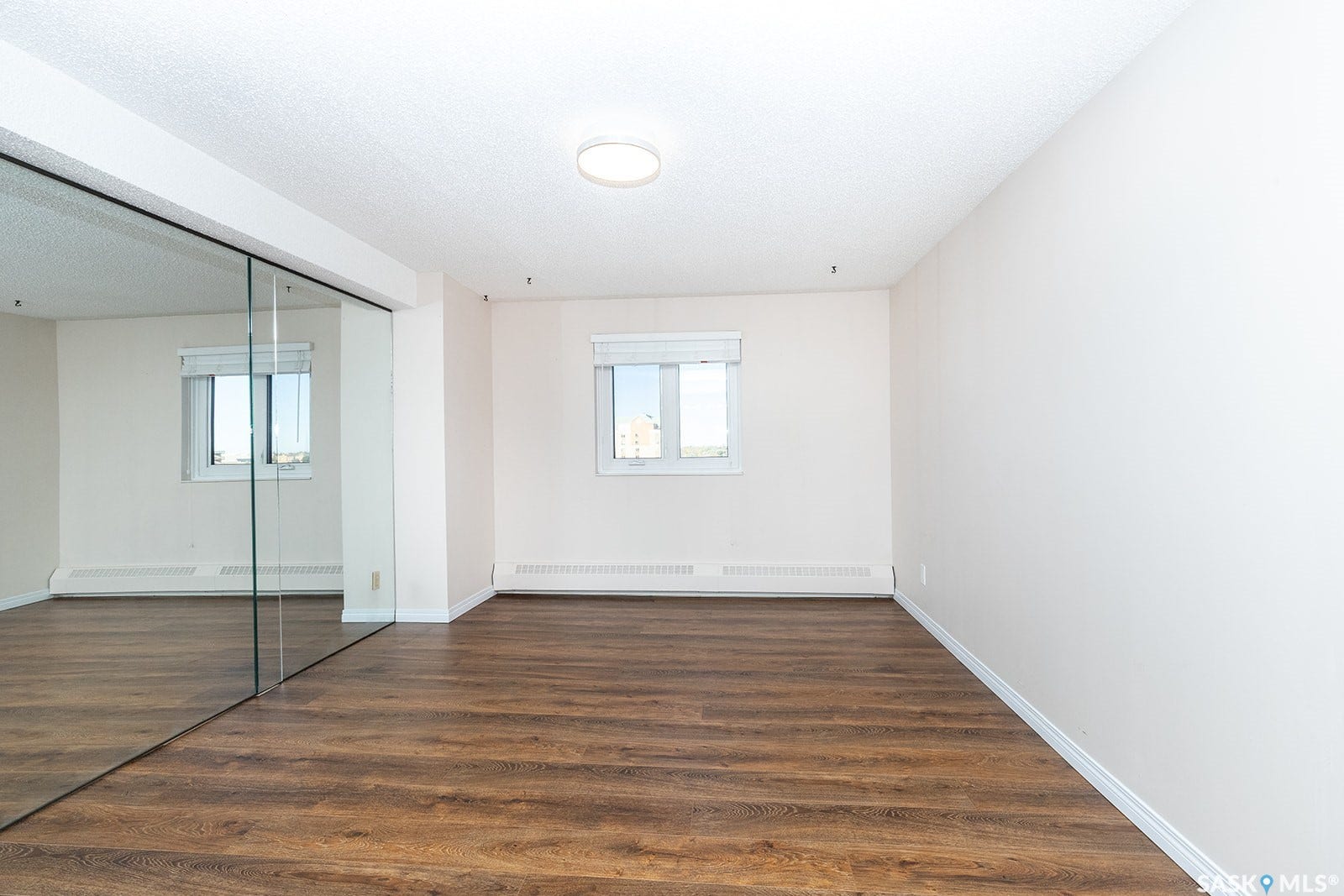 Laminate flooring, white walls, and large mirrored closet