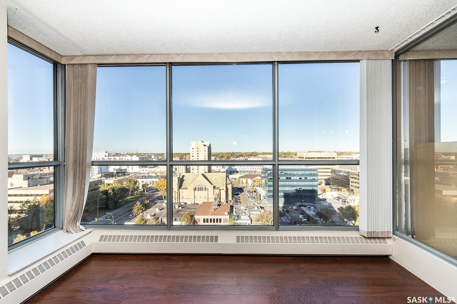 Large windows wall with city view, and dark laminate flooring