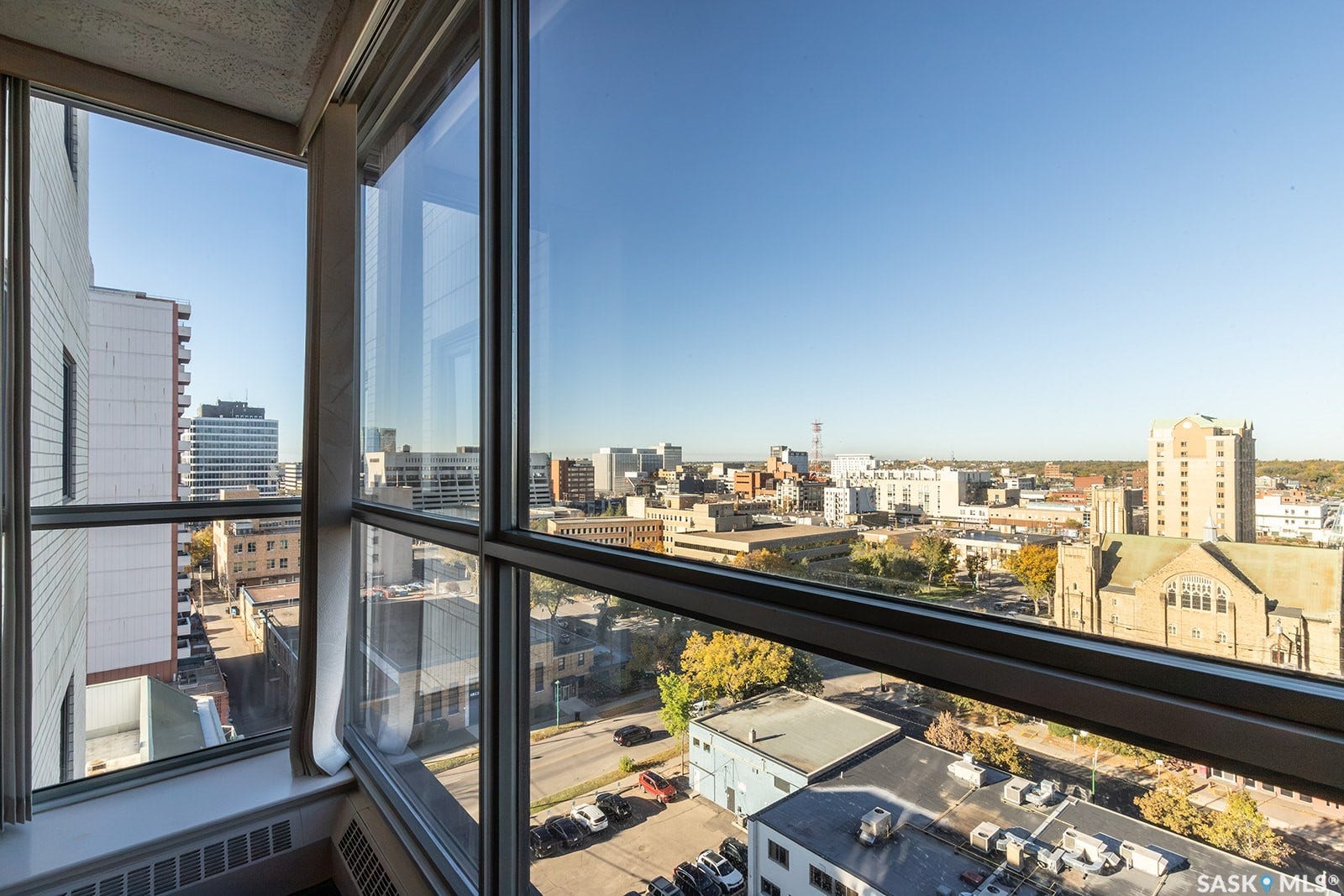 Large windows in living room with city view, and dark laminate flooring